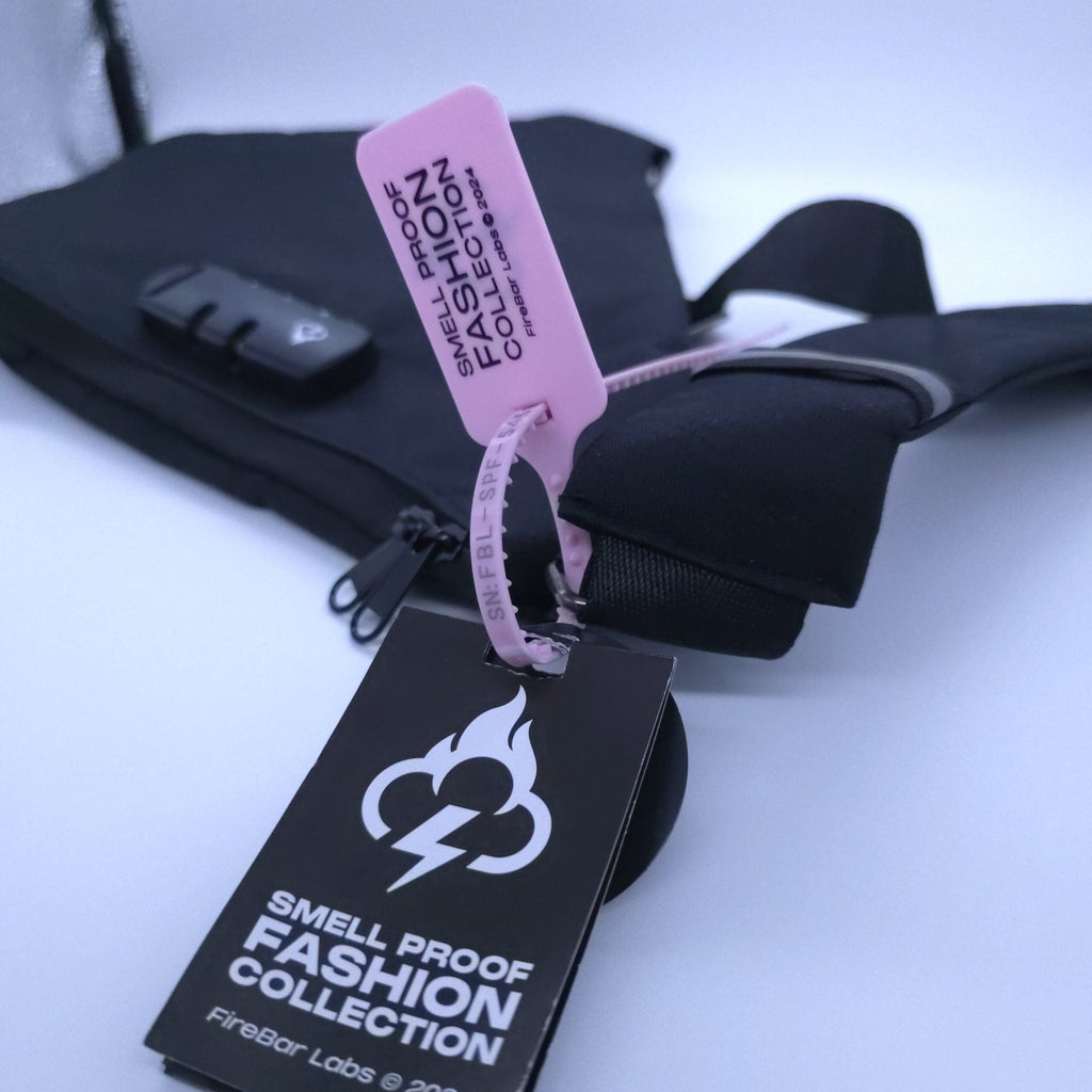 Pink camo smell-proof crossbody bag with black strap and hanging product tags