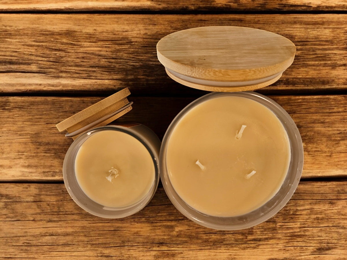 Coconut-soy candle jar open with exposed wax and wicks, plus two small tins, lid aside