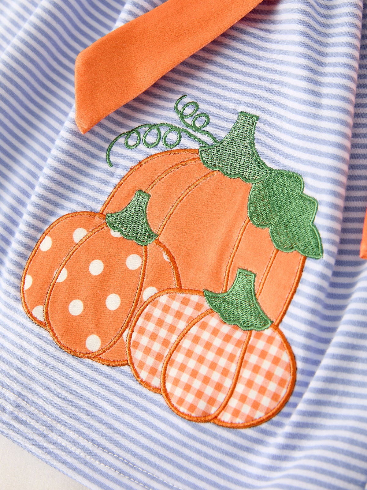 Pumpkin applique on blue-and-white striped dress with orange and green details