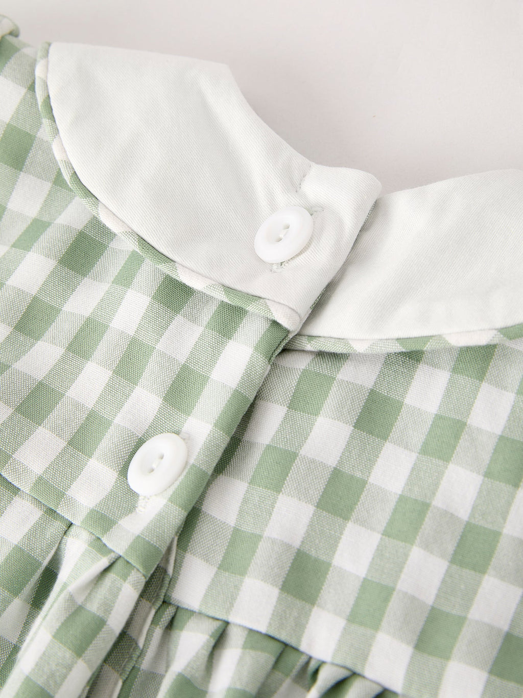 White button placket with scalloped ruffle edge on green gingham dress