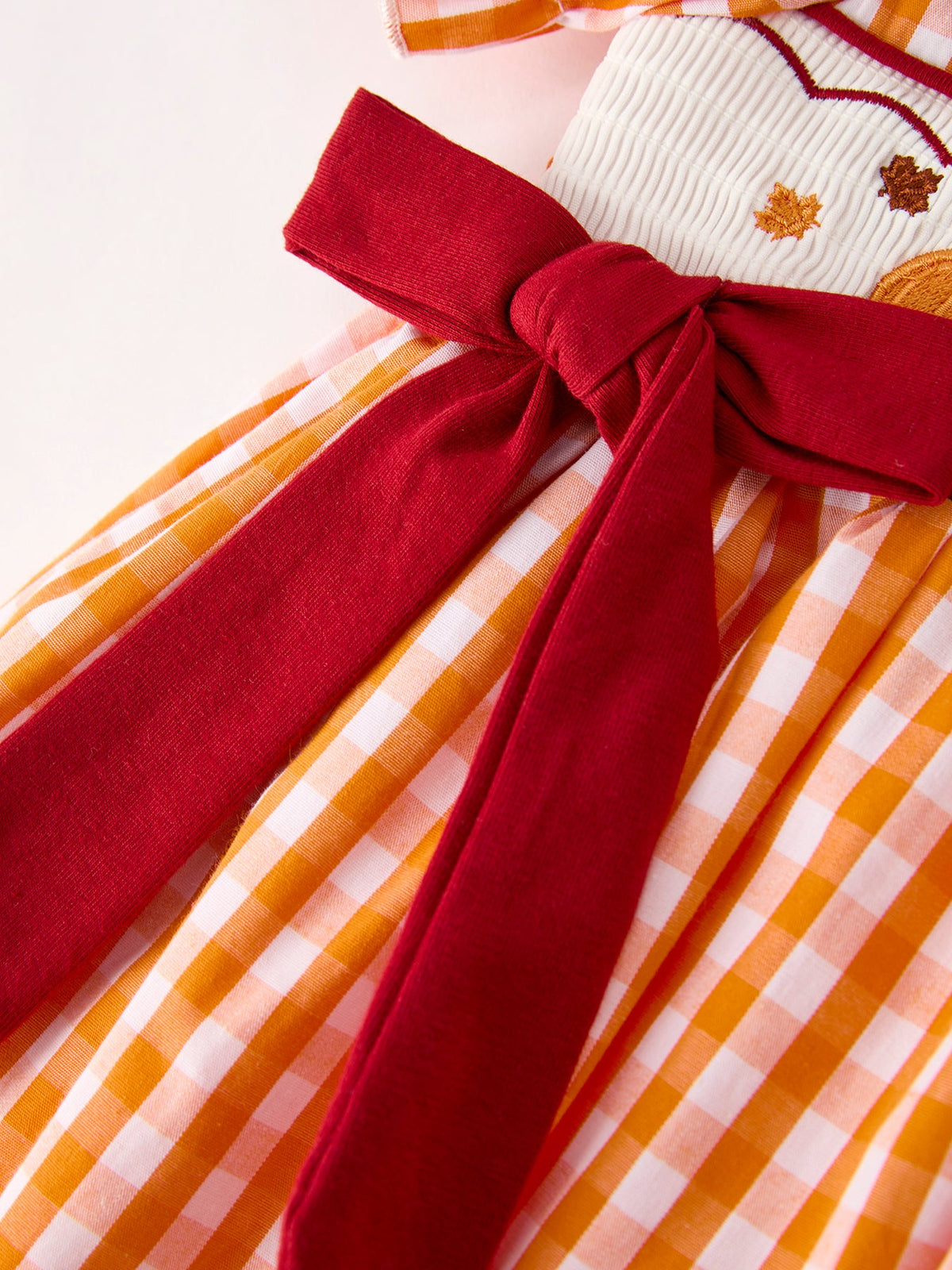Girls orange checkered dress with oversized red bow waist detail
