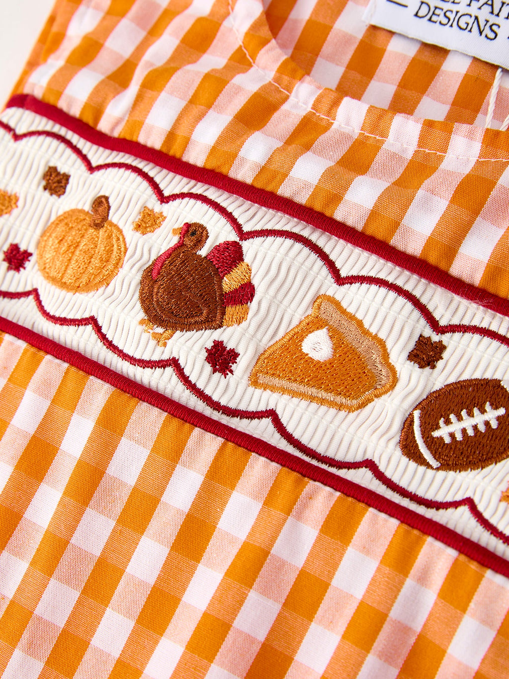 Embroidered fall icons on orange gingham romper trim: turkey, pumpkin, football