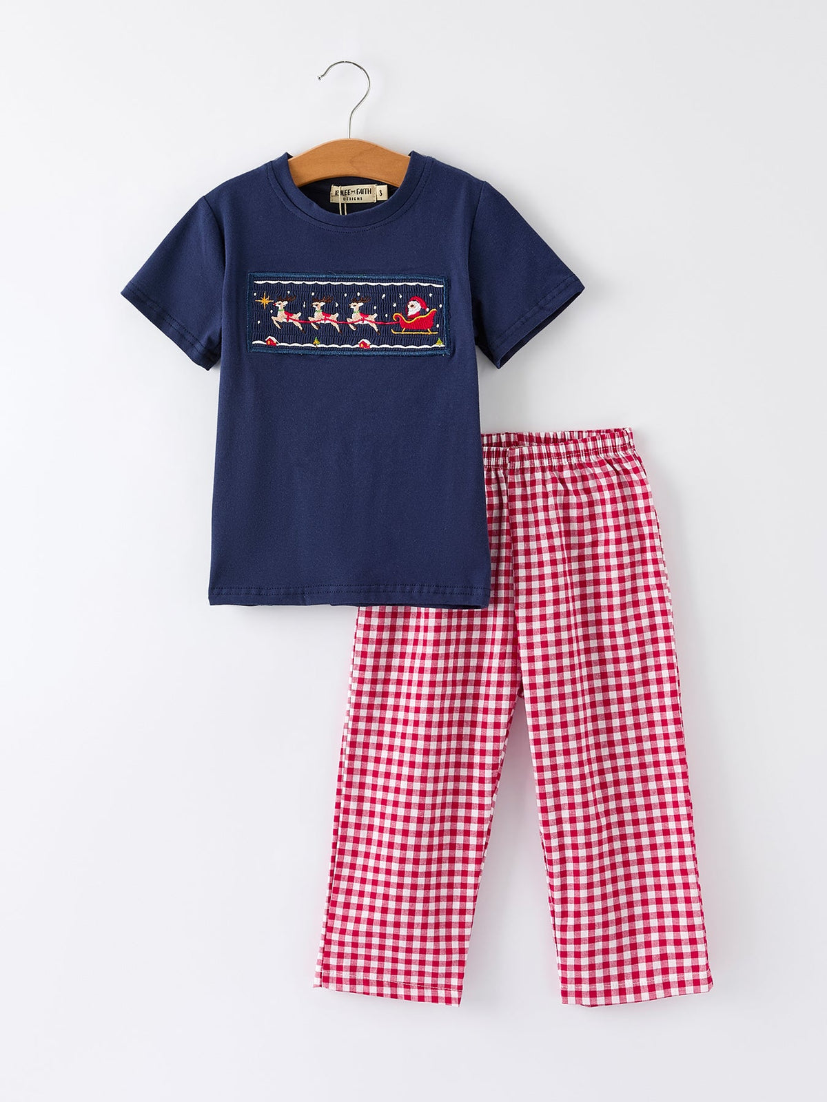 Boys navy T-shirt with Santa sleigh print and red check plaid pajama pants, flat lay