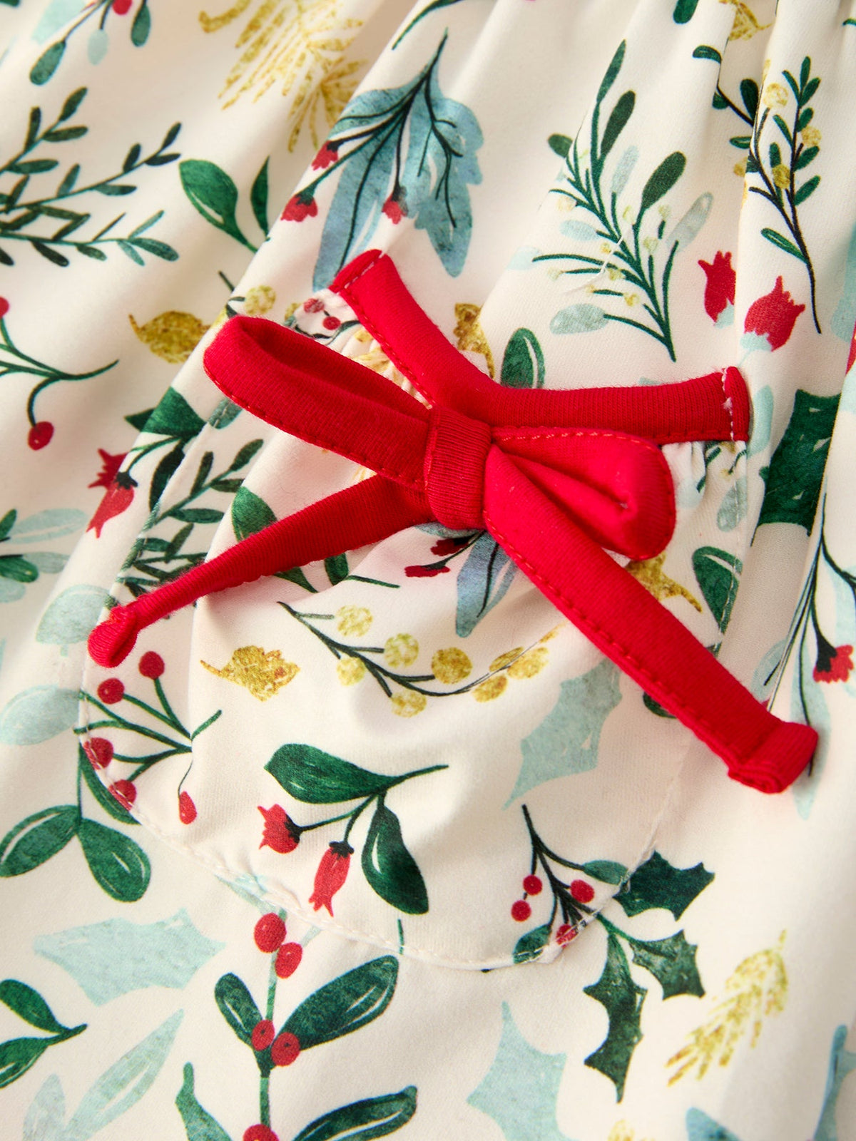 Cream toddler Christmas dress with red bow at waist, holiday floral print