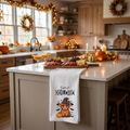 White Halloween tea towel with cute highland cow graphic, hanging on kitchen cabinet