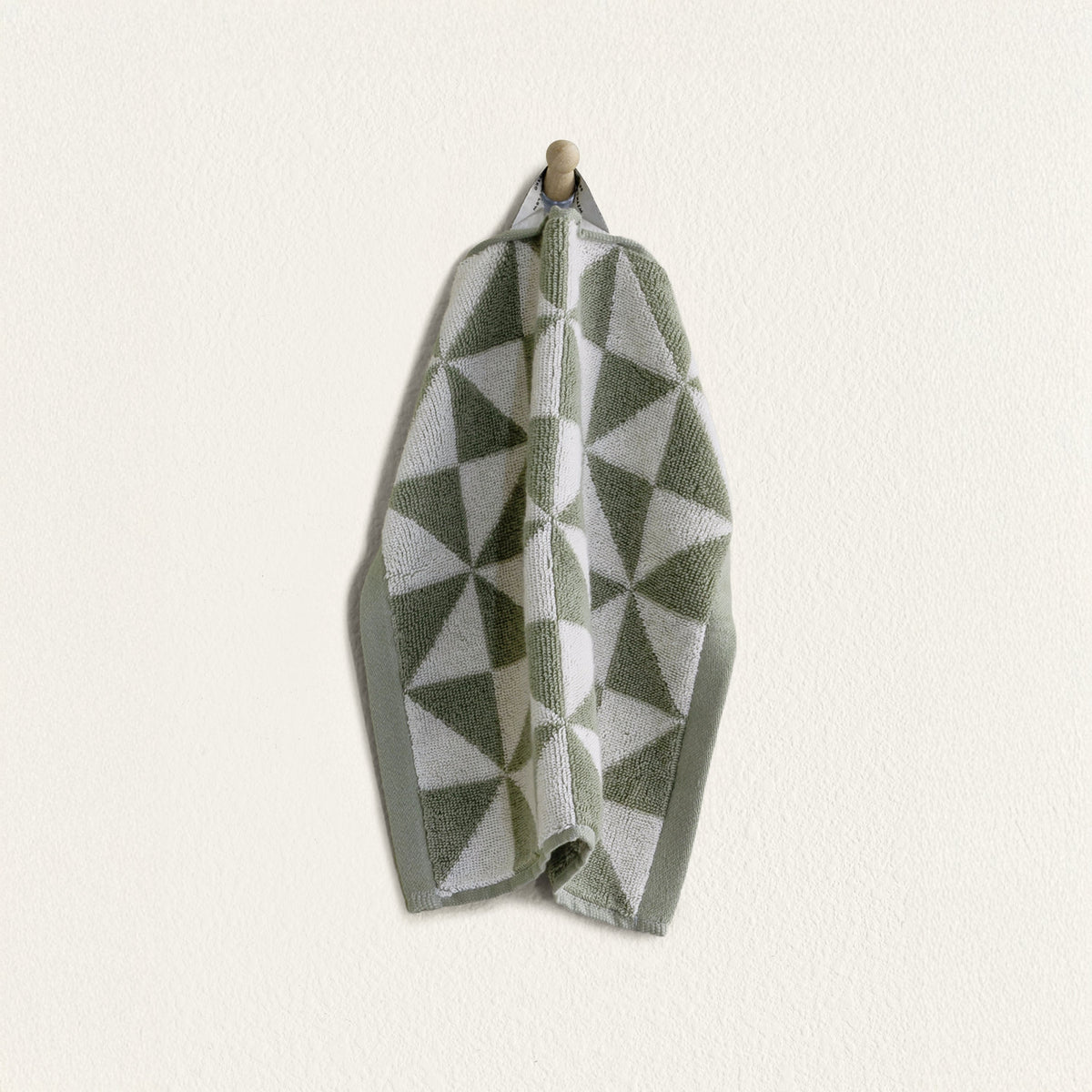 Sage and ecru geometric cotton towel folded with visible hem and pattern