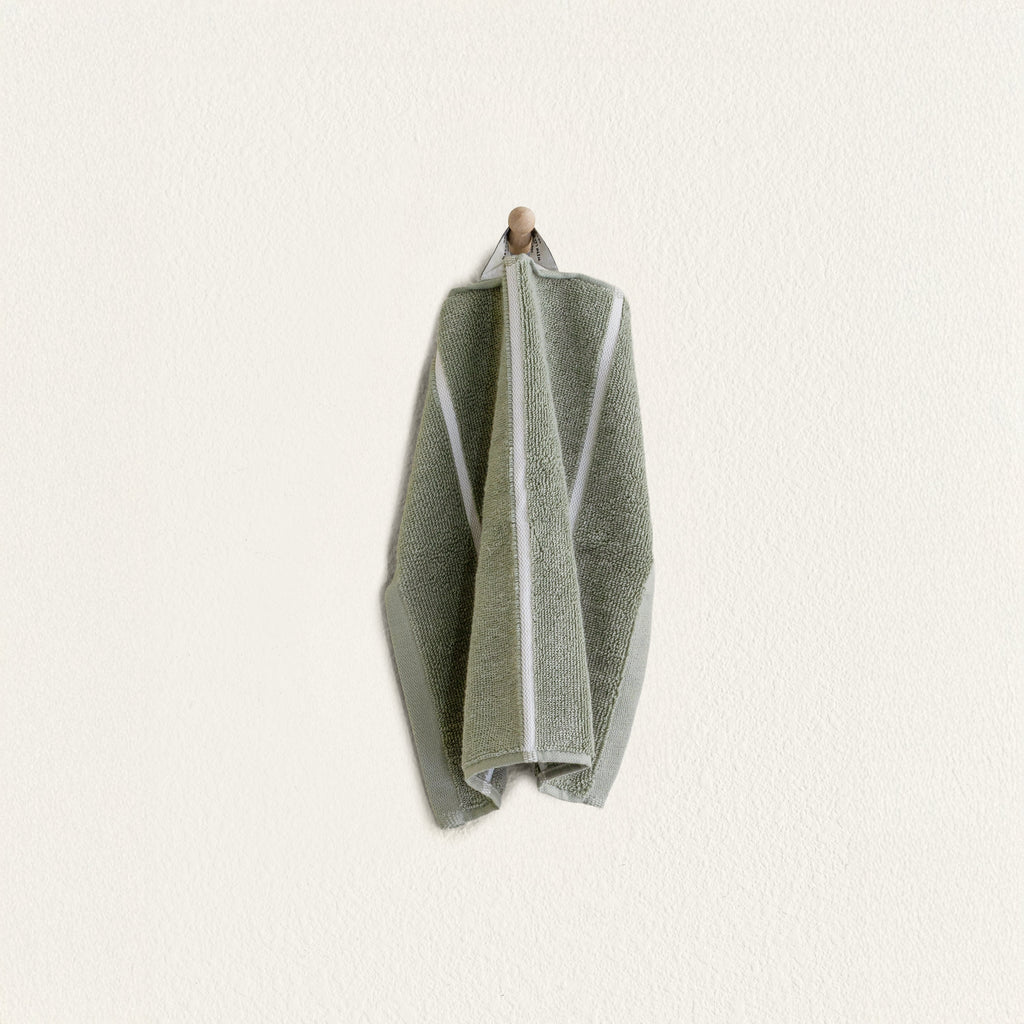 Folded sage green cotton towel with ecru border panel