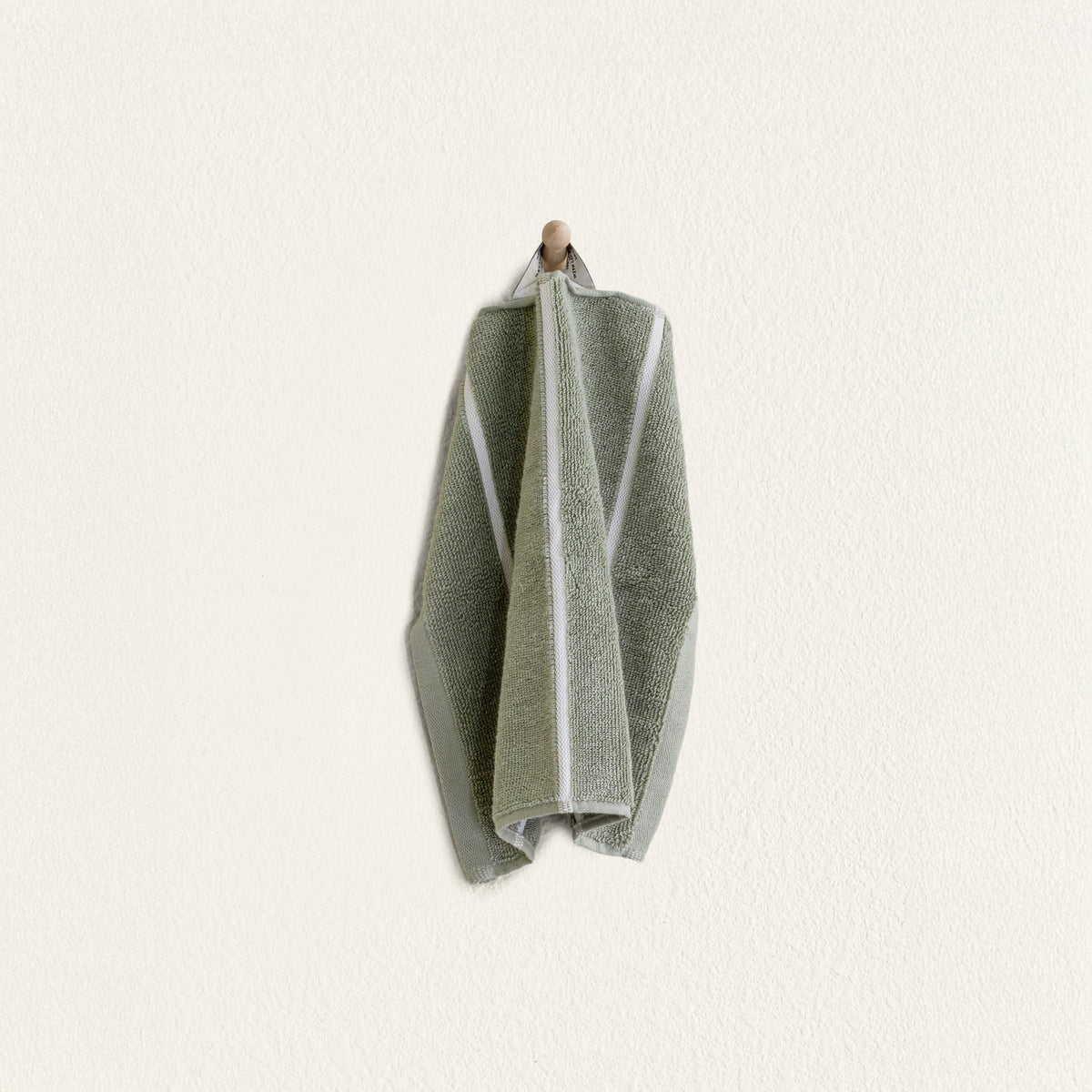 Folded sage green cotton towel with ecru border panel