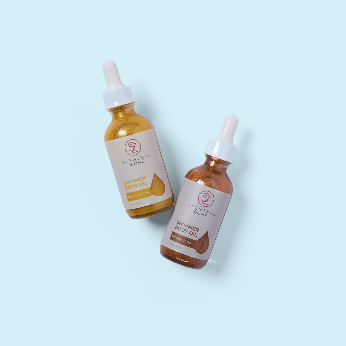 Two amber shimmer body oil bottles with droppers and gold liquid