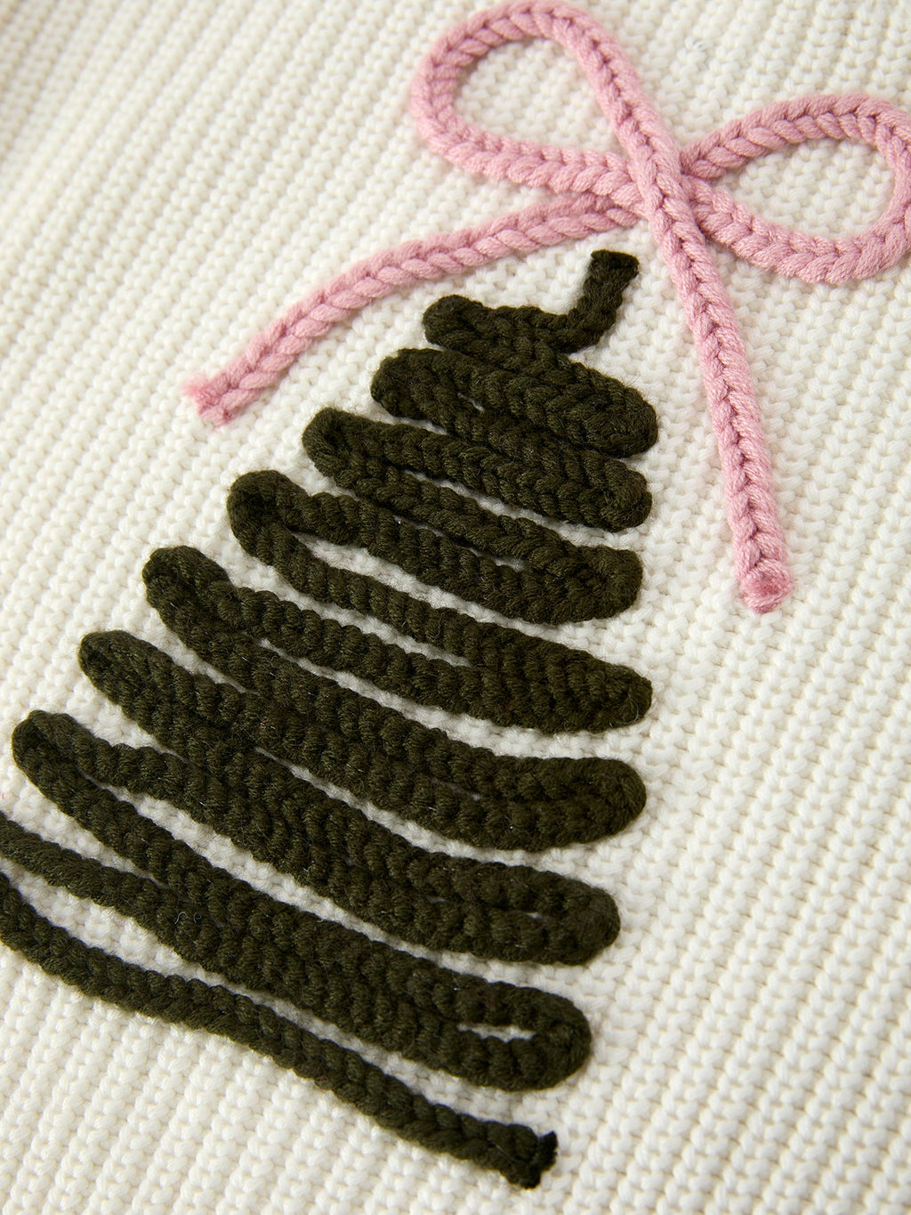 Cream knit sweater detail: dark tree graphic with pink bow
