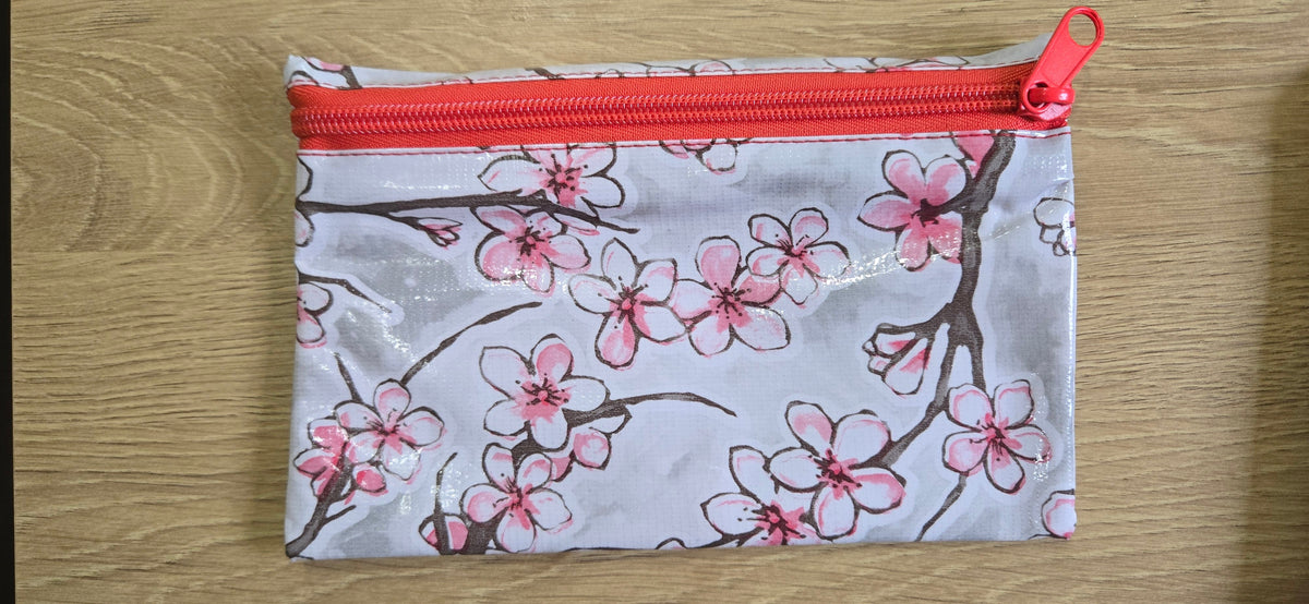 White floral zippered pouch with pink blossoms and red zipper