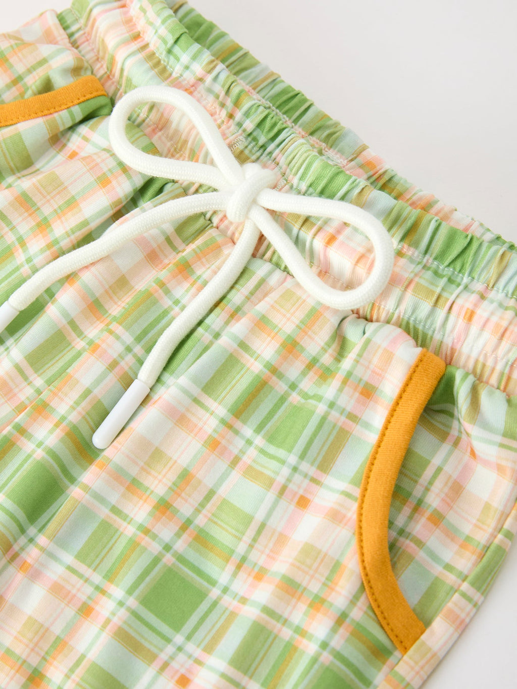 Green plaid pants with white drawstring and elastic smocked waistband; orange trim