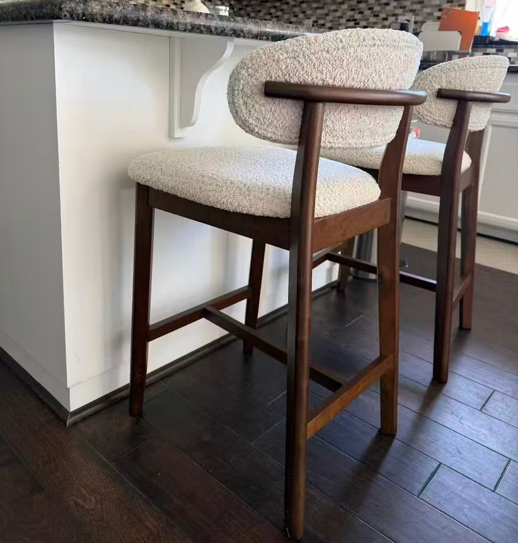 Cream upholstered bar stool with arched backrest and dark wood legs