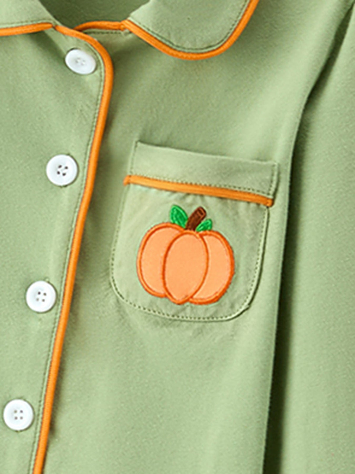 Kids' green pajama top with orange pumpkin applique in chest pocket and white buttons