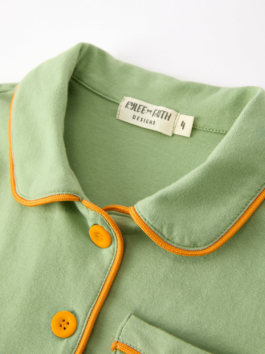 Kids' green pajama top with orange-trim collar and partial button placket, size label