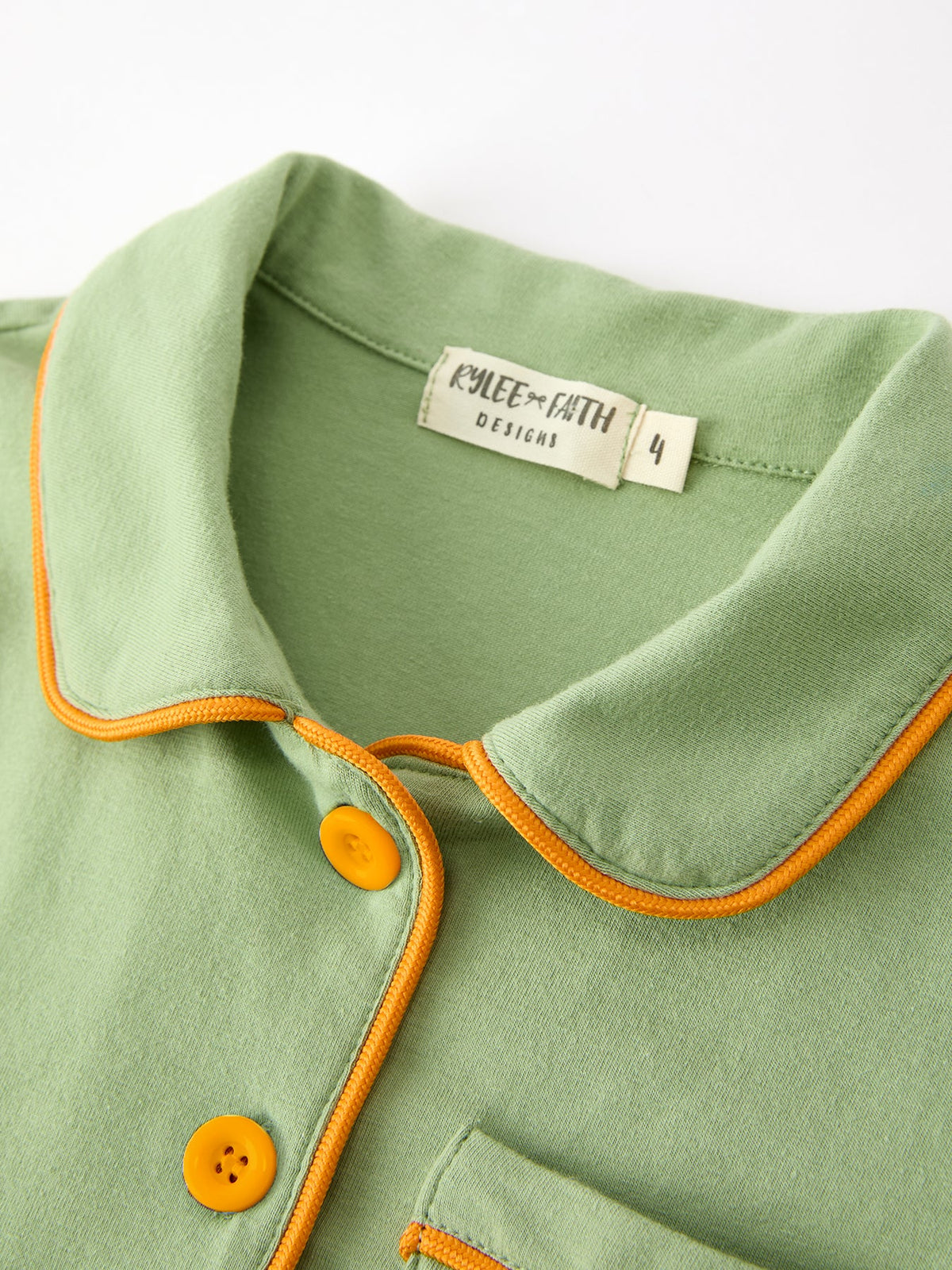 Kids' green pajama top with orange-trim collar and partial button placket, size label