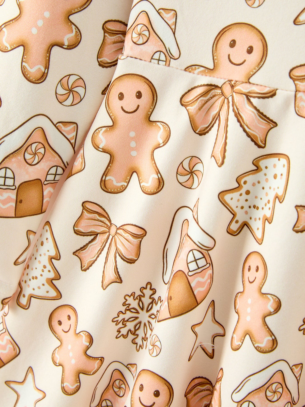 Cream fabric detail with gingerbread men, houses, stars, and snowflake shapes print