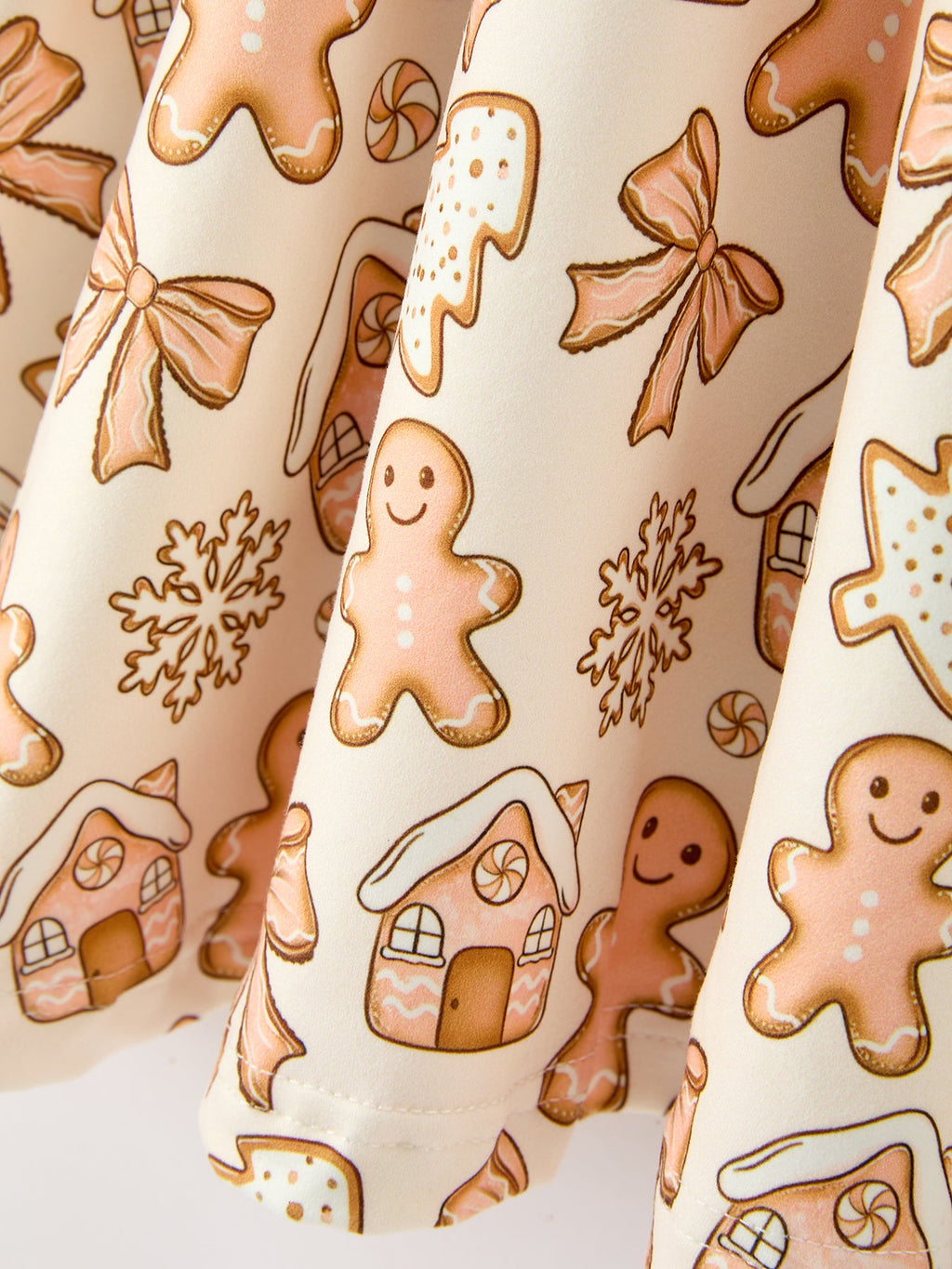 Cream fabric close-up with gingerbread men cookies, bows, and snowflakes print