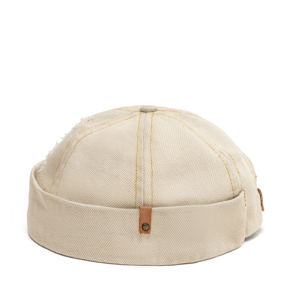 Beige canvas Docker-style cap top view with vertical stitching and brown button tab