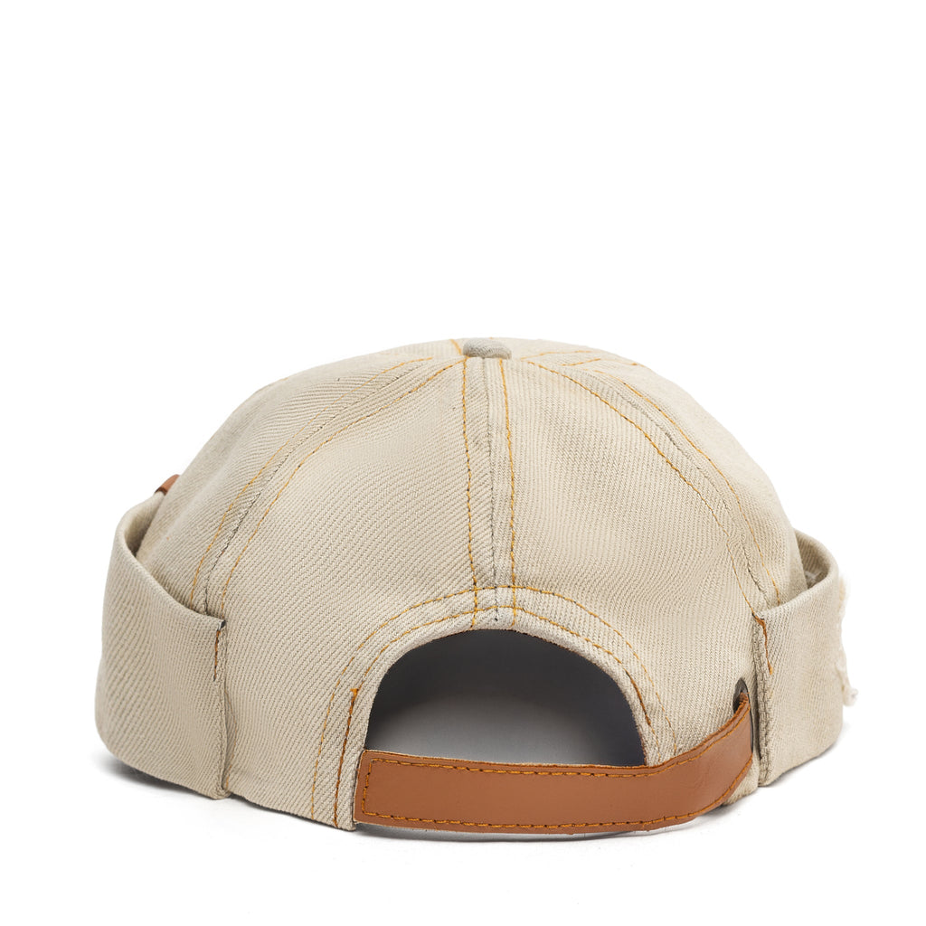Beige canvas Docker-style cap with interior opening and brown leather rim
