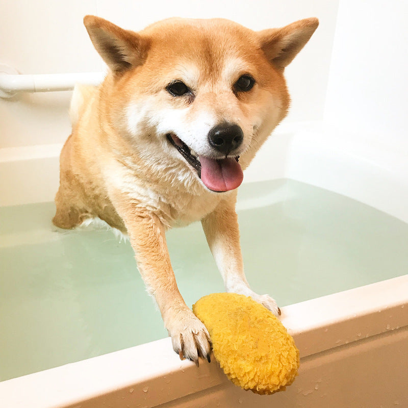Dog holding yellow shrimp-shaped stuffed chew toy with orange fin