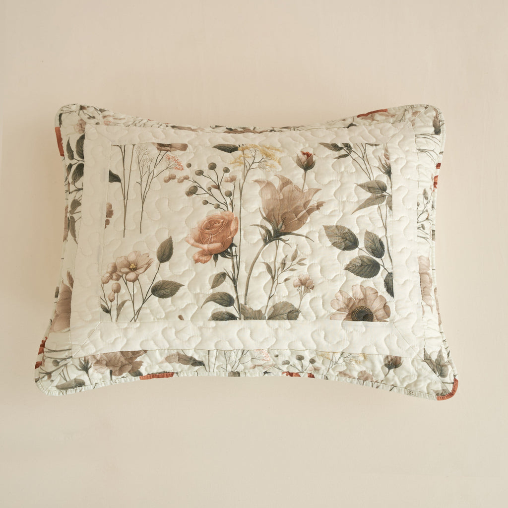 Floral throw pillow in off-white with botanical rose and leaf pattern and quilted texture.