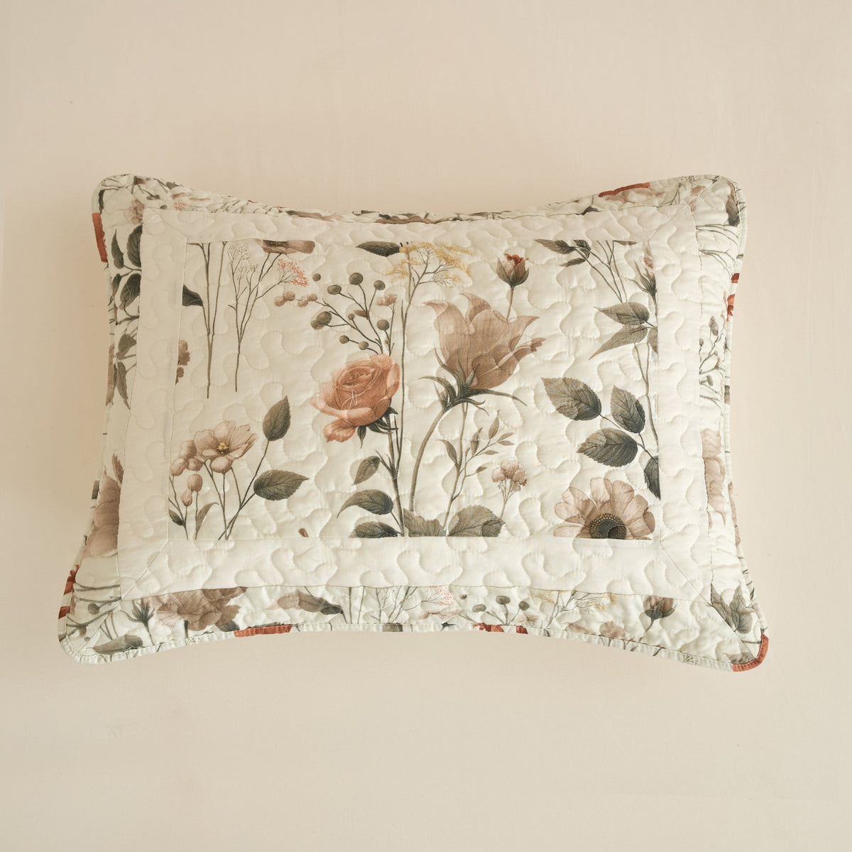 Floral throw pillow in off-white with botanical rose and leaf pattern and quilted texture.