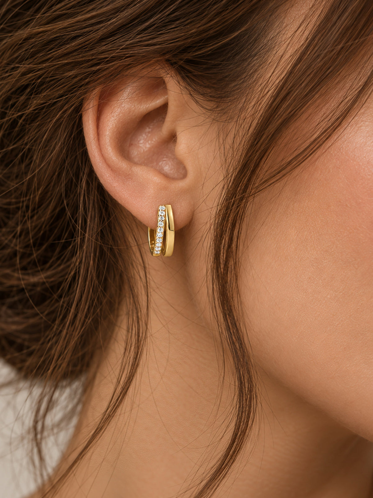 Gold-tone double pave hoop earrings with small clear stones, worn on ear