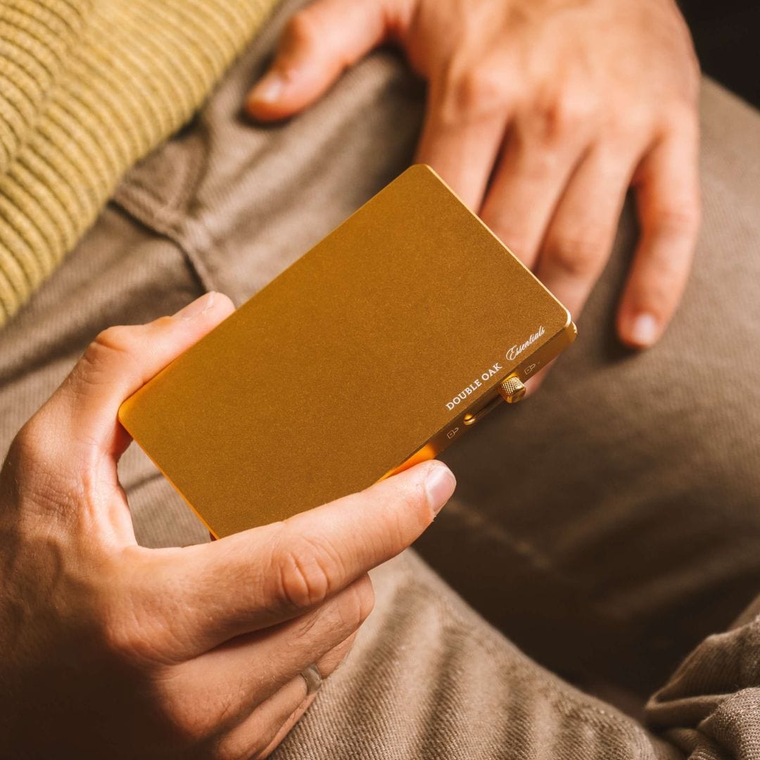 Tan pop-up cardholder held in hands with visible logo on front.