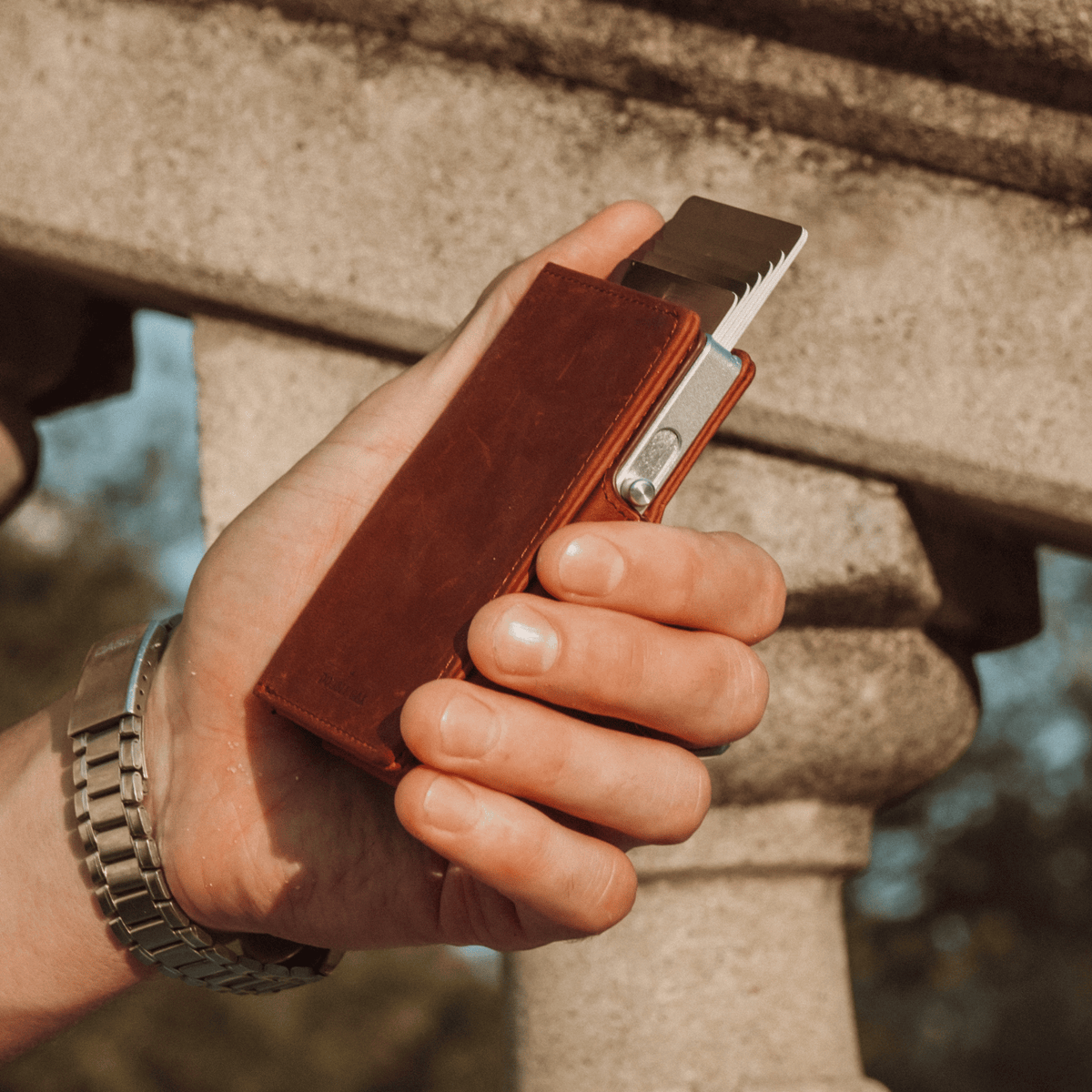 Brown leather bifold wallet with cards and metal clasp partially visible