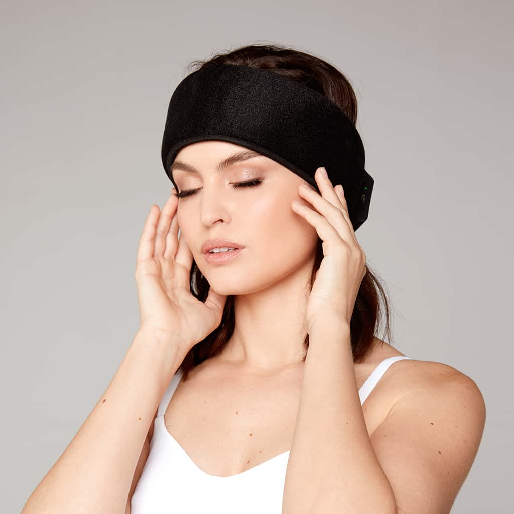Black fabric headband with NeuroWrap logo, worn by model with hands near face