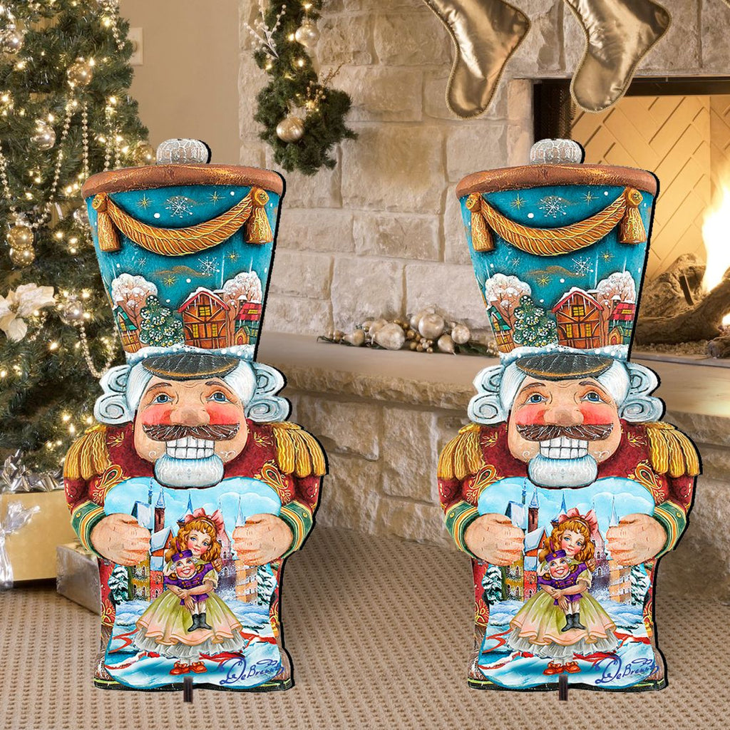 Pair of painted nutcracker yard decorations with blue tops, red coats, holding dolls