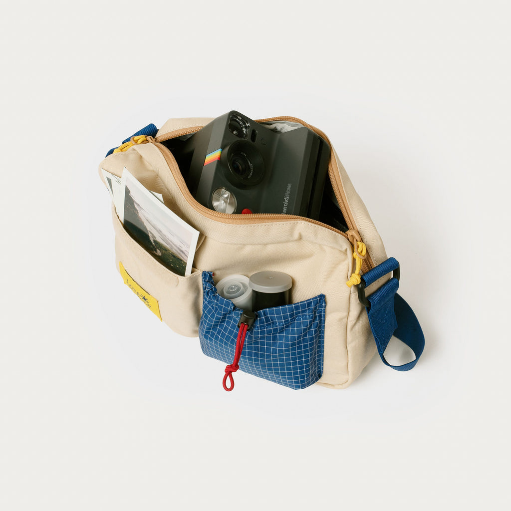 Cream shoulder bag with blue front pocket and organizer-style compartments