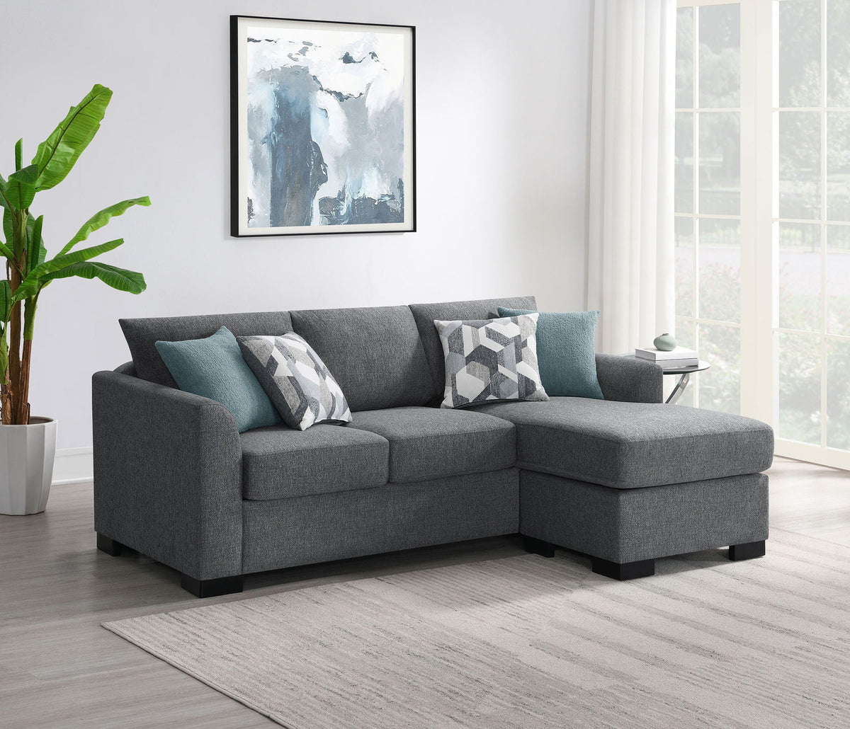 Grey sleeper sectional chaise sofa with teal pillows and geometric patterned cushion covers