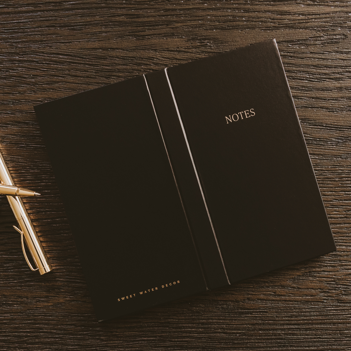 Black notes booklet with gold “NOTES” title and vertical divider lines on the cover.