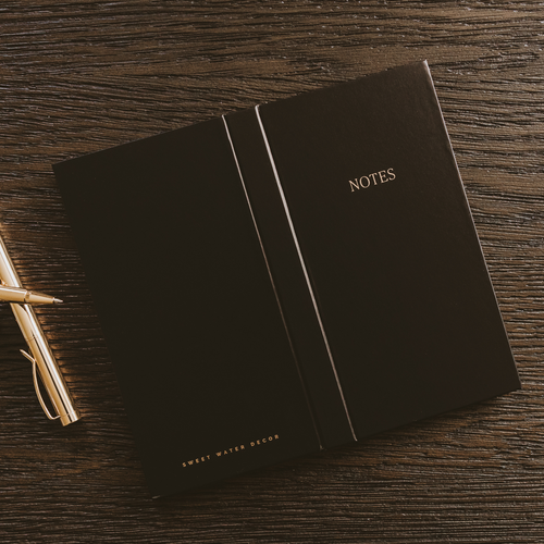 Black notes booklet with gold “NOTES” title and vertical divider lines on the cover.