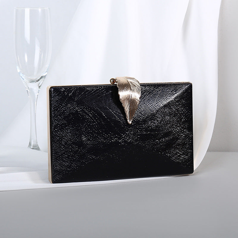 Black textured small evening crossbody bag with gold-tone bow clasp.