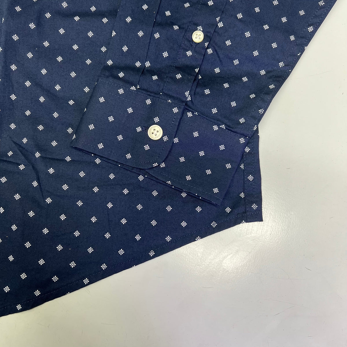 Navy button-up shirt with small white daisy pattern and white button detail.