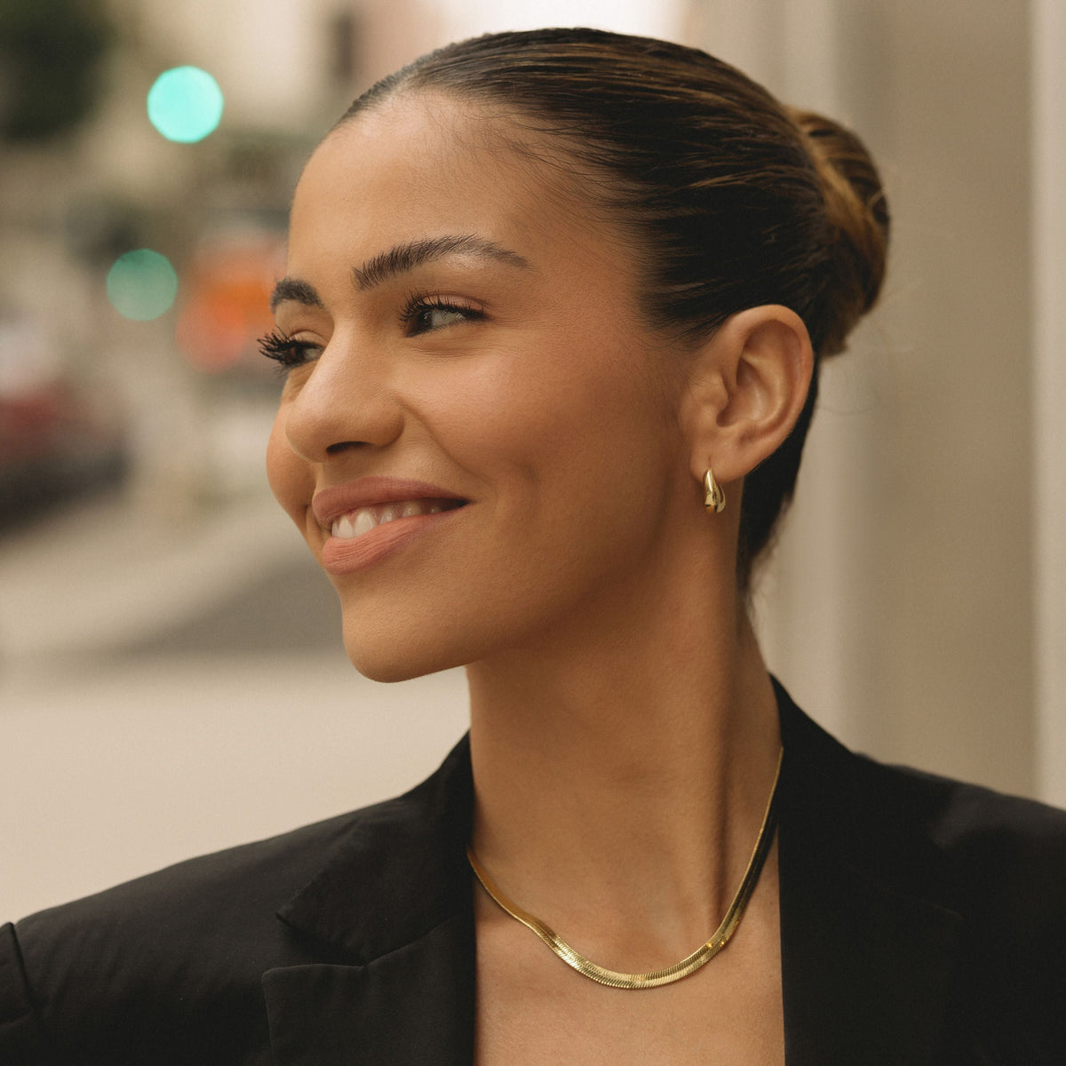 Gold herringbone chain necklace on the neck with a smooth, flat chain texture