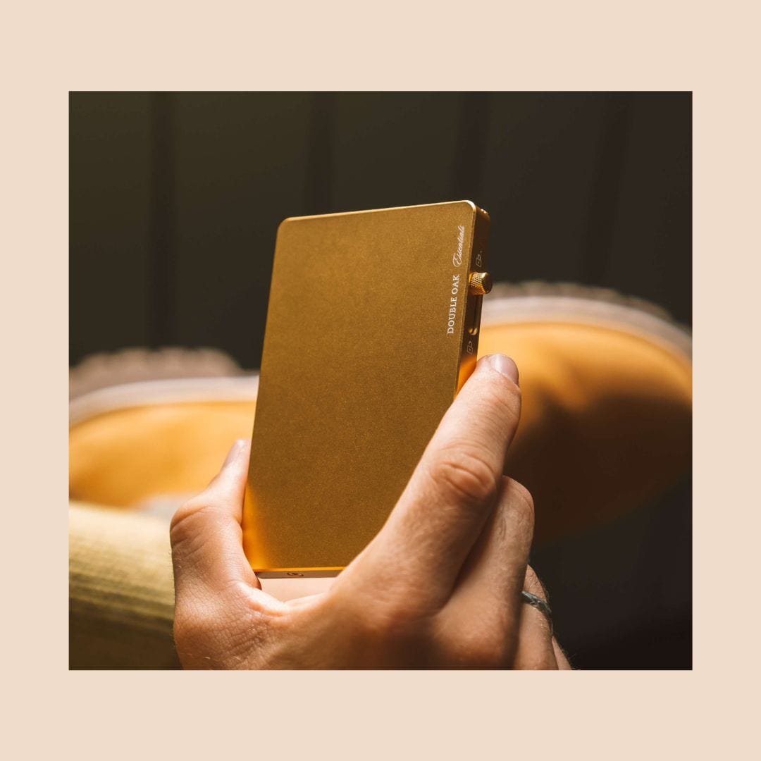 Gold pop-up cardholder with brass button closure, held in hand.