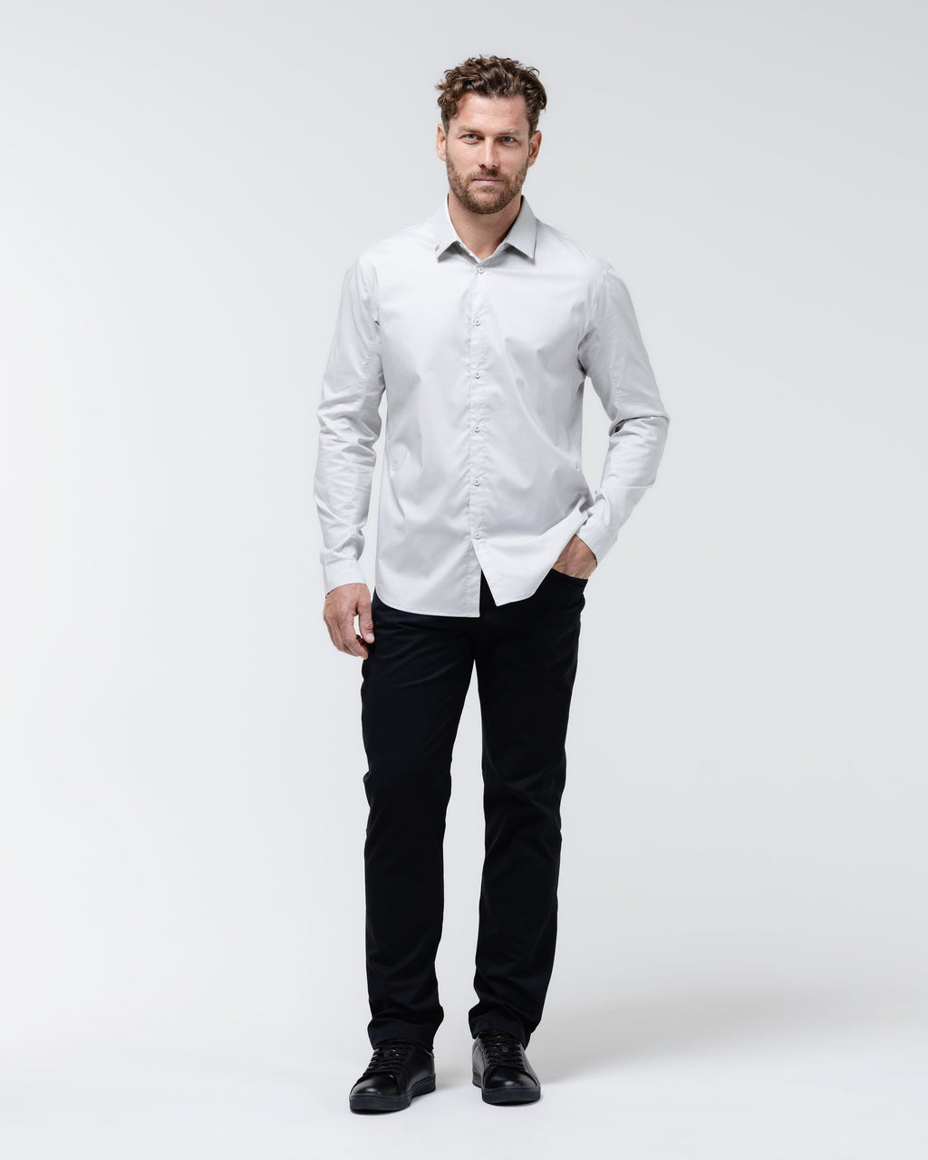 Man wearing black chino pants with belt loops and dark sneakers.