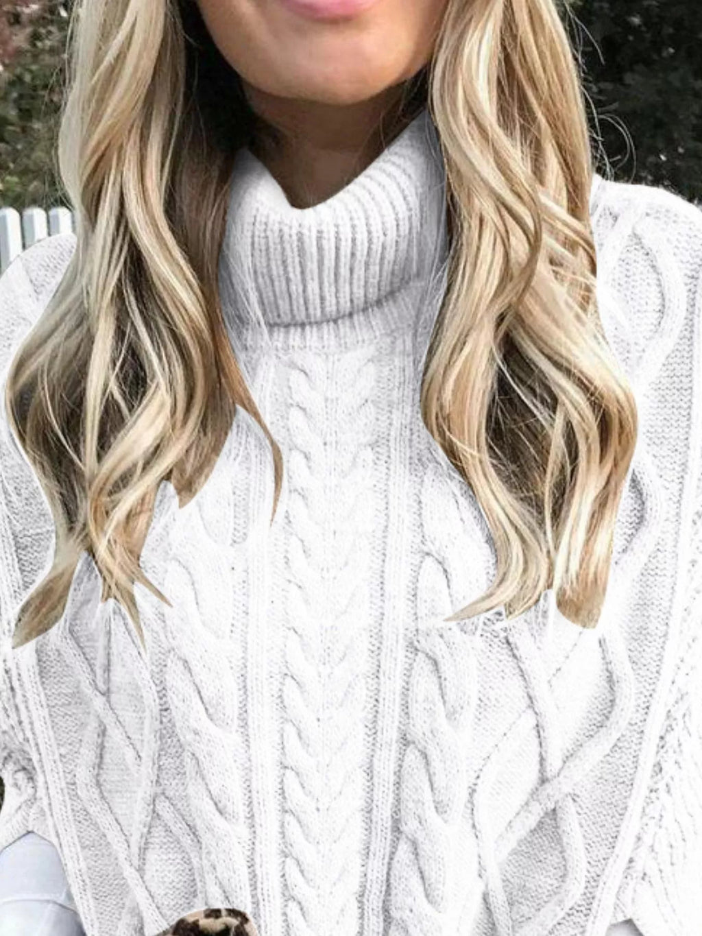 White cable-knit turtleneck poncho cover-up close-up with raised cable pattern