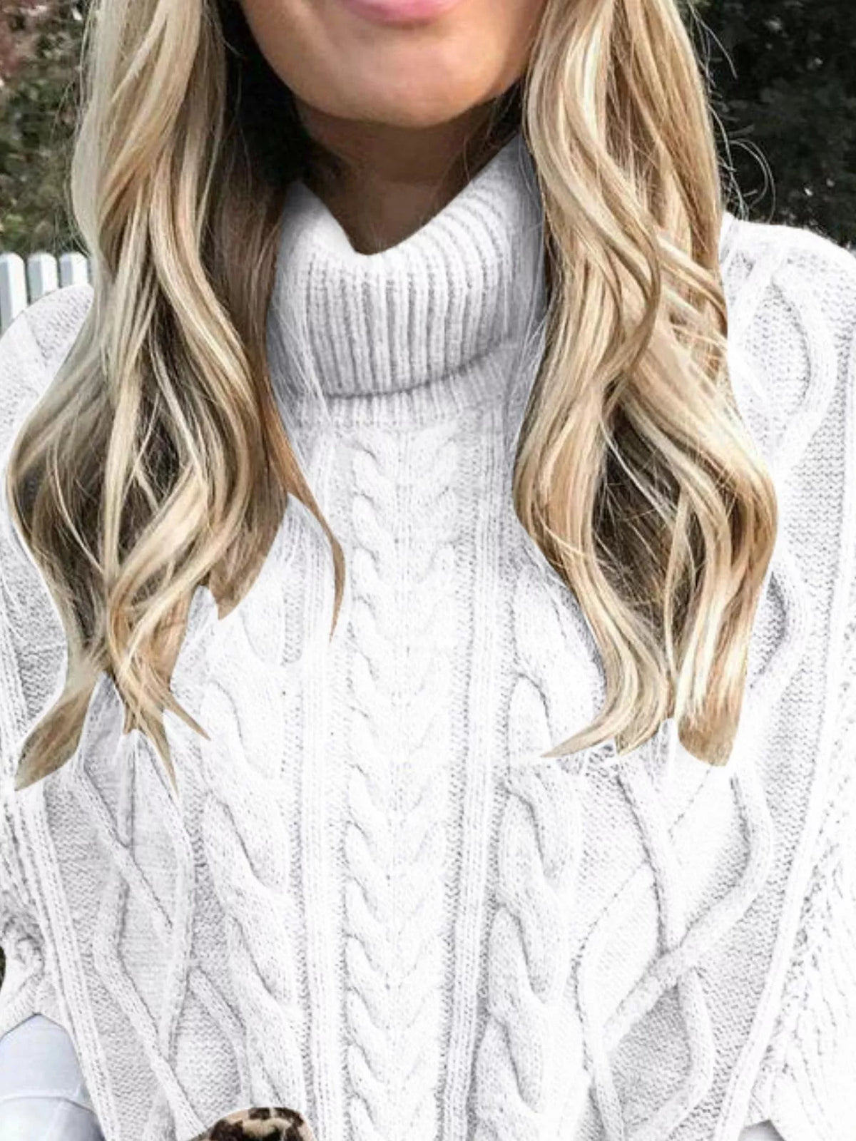 White cable-knit turtleneck poncho cover-up close-up with raised cable pattern