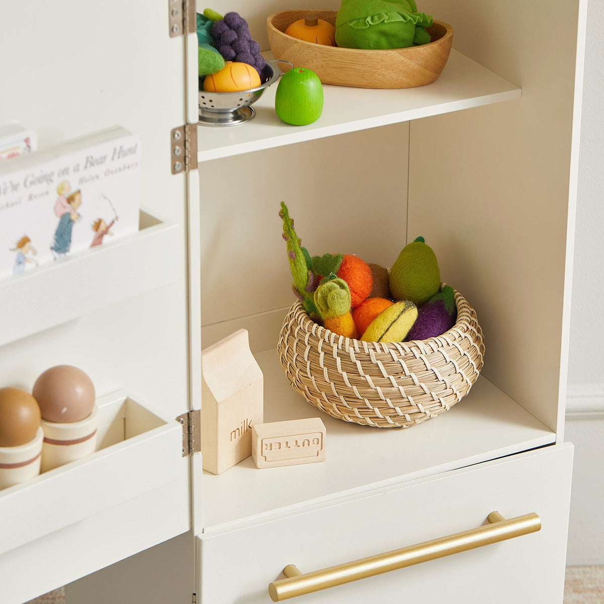 White play kitchen refrigerator cabinet with open shelf and toy produce basket