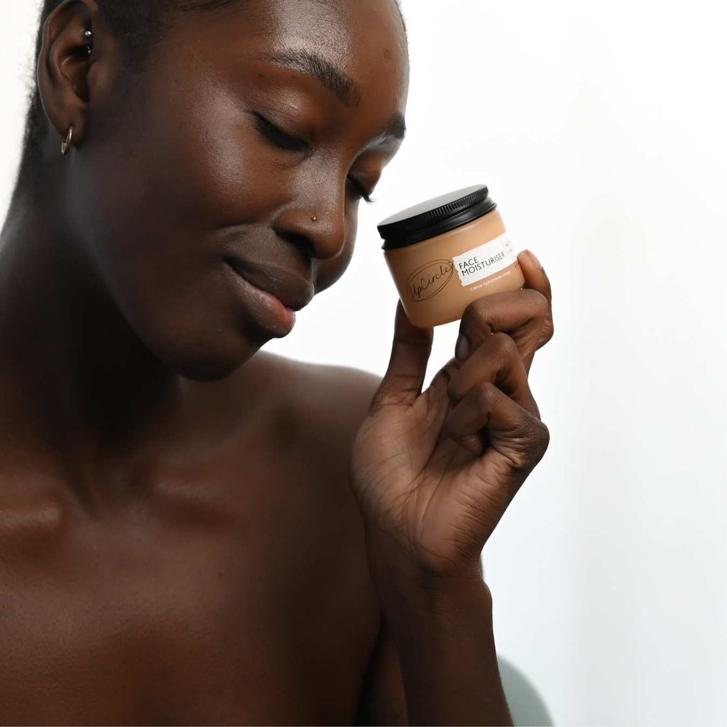 Woman holding a face moisturizer jar and rubbing cream on her skin