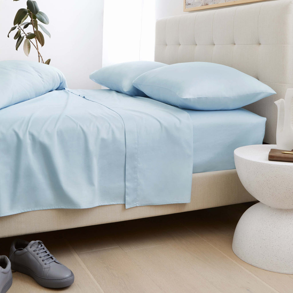 Light blue sateen pillowcases on a bed with coordinated light blue duvet