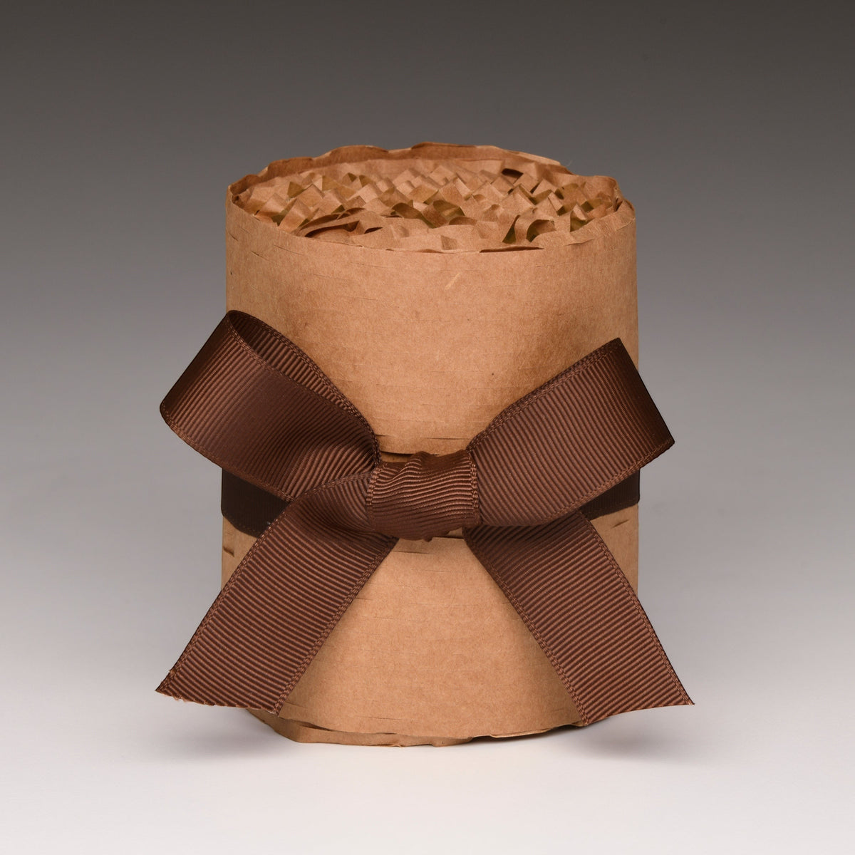 Kraft paper candle jar wrap with brown ribbon and bow, unlit