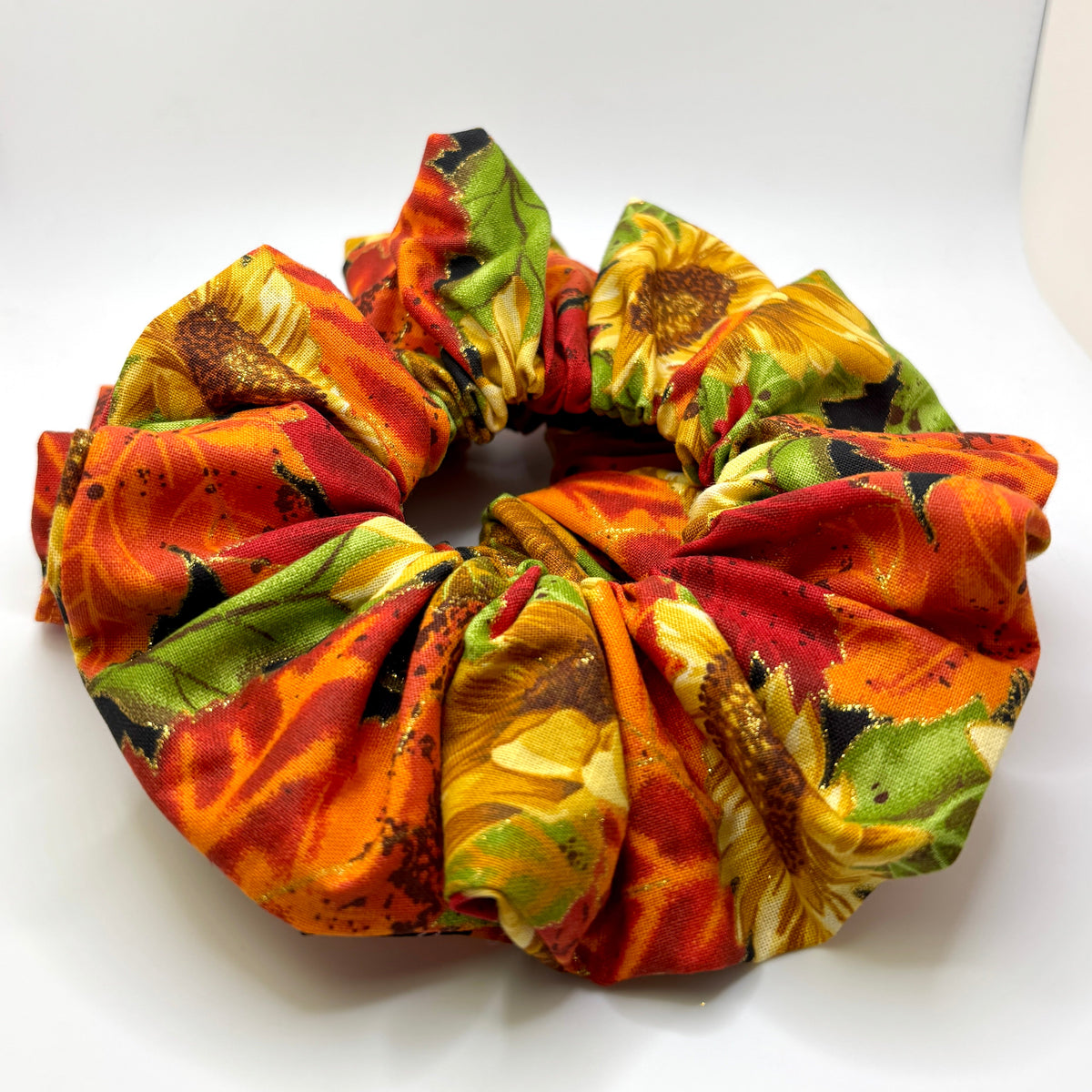 Sunflower-pattern scrunchie with orange, red, and green fabric gathered in a circle