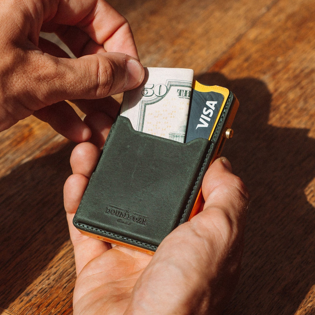 Dark green leather mod wallet holding cash and cards, gold-tone frame