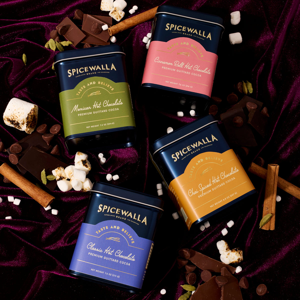 Assorted Spicewalla hot chocolate mix tins, including chai spiced, on dark cloth